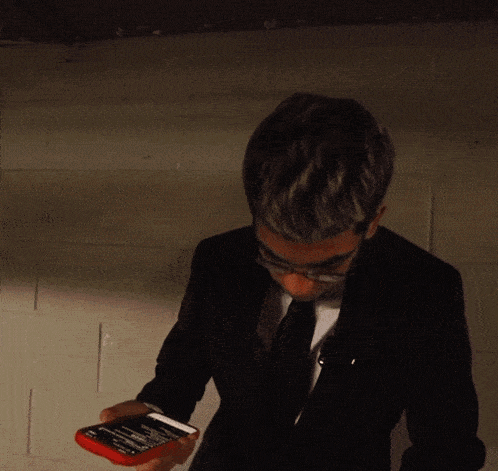 a man in a suit and tie holds a cell phone in his hand