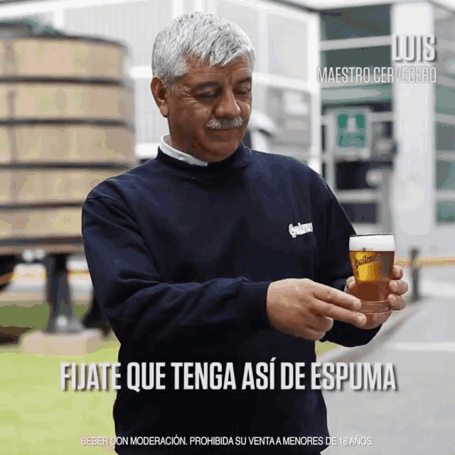 a man in a blue shirt is holding a glass of beer and says " fijate que tenga así de espuma "