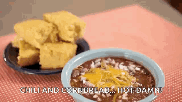 a bowl of chili and cornbread on a table next to a bowl of chili and cornbread .
