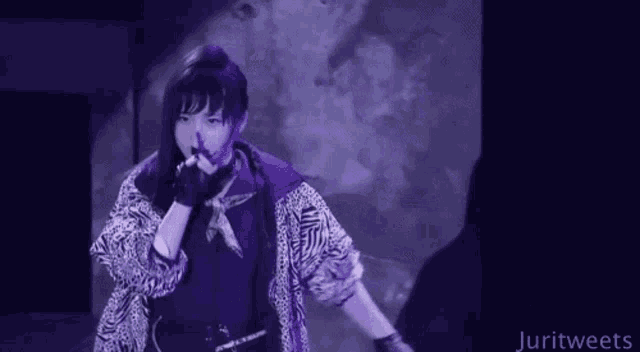 a woman in a zebra print jacket is singing into a microphone on stage .