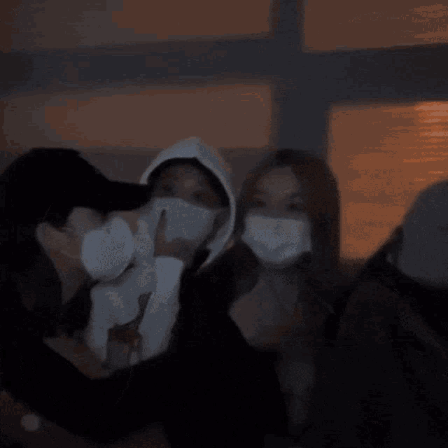 a woman wearing a mask is hugging a man wearing a hat