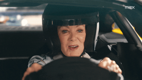 a woman wearing a helmet is driving a car and the word max is on the bottom right