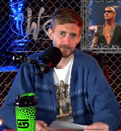 a man sitting in front of a microphone with a green shaker that says g1 on it