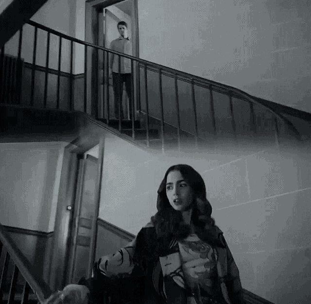a black and white photo of a man and a woman walking down stairs