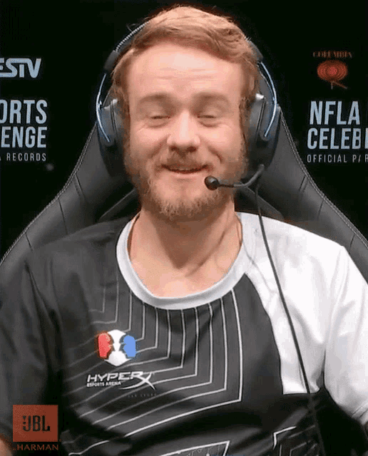 a man wearing headphones and a hyperx shirt smiles with his eyes closed