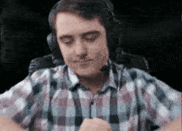 a man wearing headphones and a plaid shirt is sitting in a chair
