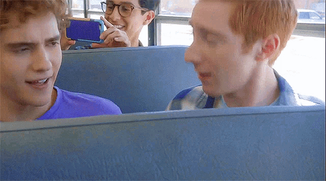 a man taking a picture of another man with a blue phone
