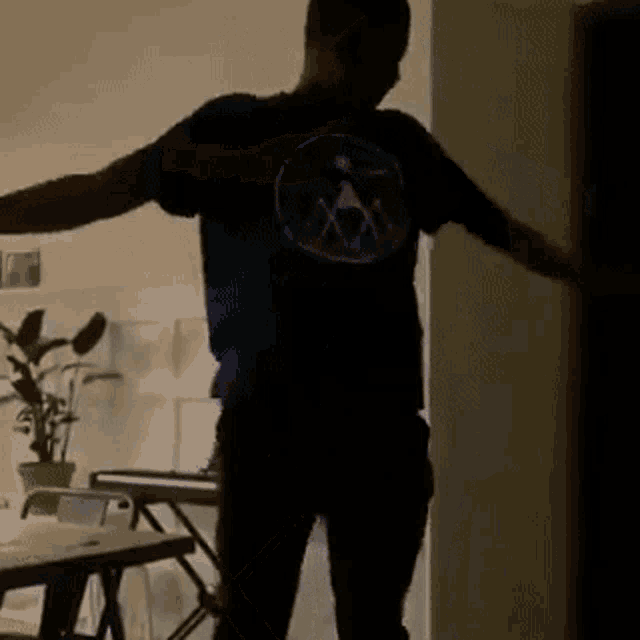 a man in a blue shirt is dancing in a living room .