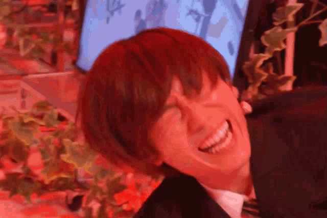 a man with red hair is smiling in front of a computer monitor