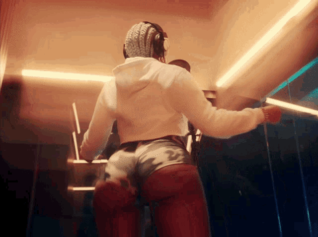 a woman in a white hoodie and shorts is dancing in a dark room