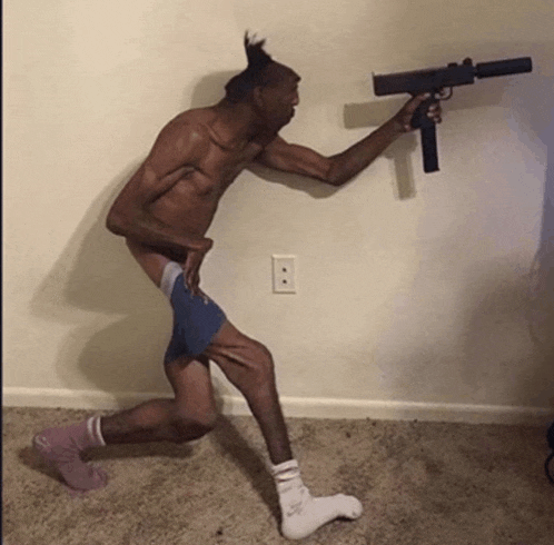 a shirtless man is holding a gun in front of a wall