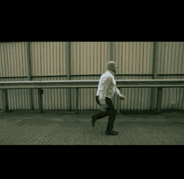 a man in a white shirt and black pants is running on a concrete surface
