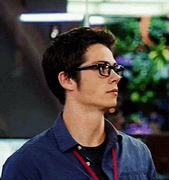 a young man wearing glasses and a blue shirt is looking to the side