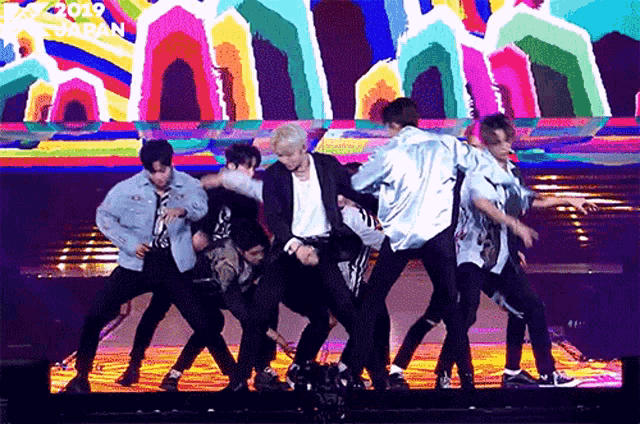 a group of young men are dancing on a stage with a sign that says " 2019 japan " in the background