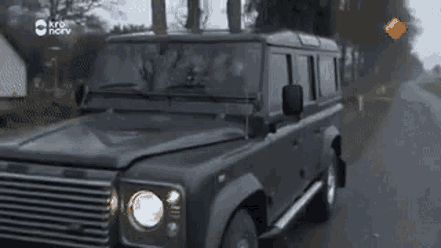 a black land rover is driving down a road .