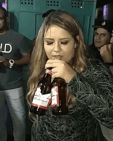 a woman is drinking from a bottle of budweiser beer