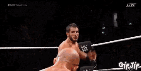 a wrestler is laying on the ground in a wrestling ring while a referee watches .