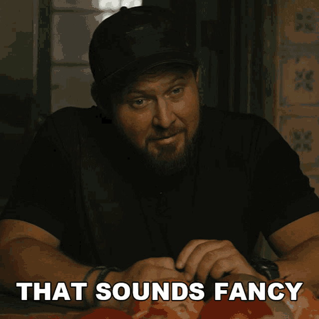 a man is sitting at a table with the words that sounds fancy behind him