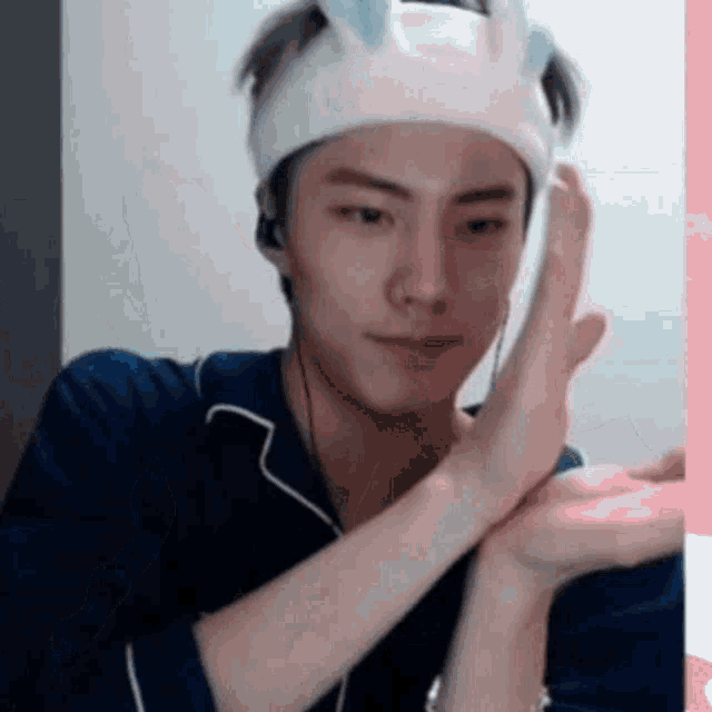 a young man wearing a headband with bunny ears is making a peace sign .