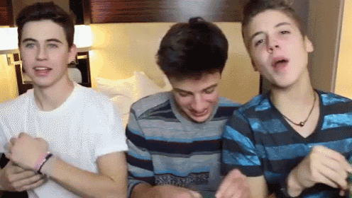 three boys are standing next to each other in a room