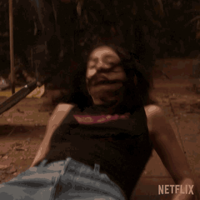 a woman in a black tank top is laying on the ground with a netflix logo in the corner