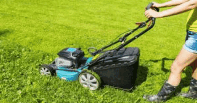 a woman is using a lawn mower to cut the grass in her yard .