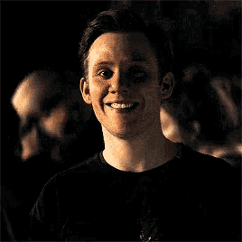 a man in a black shirt is smiling and looking at the camera .