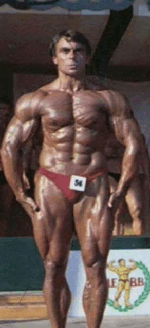 a bodybuilder with the number 34 on his underwear poses for a picture