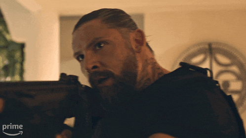 a man with a beard is holding a gun and the word prime is on the bottom right