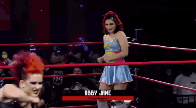 a female wrestler named abby jane stands in a wrestling ring