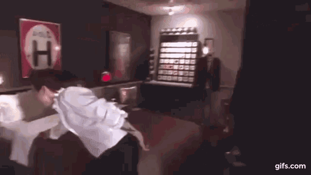 a man in a white shirt and black pants is standing in a bedroom .