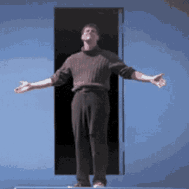 a man with his arms outstretched stands in front of a blue door