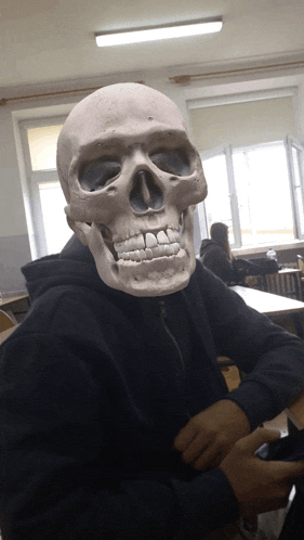 a person wearing a skeleton mask sitting at a desk