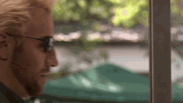 a close up of a man wearing glasses looking out of a window