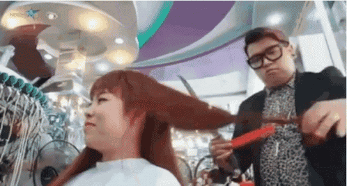 a man is cutting a woman 's hair in a hair salon .
