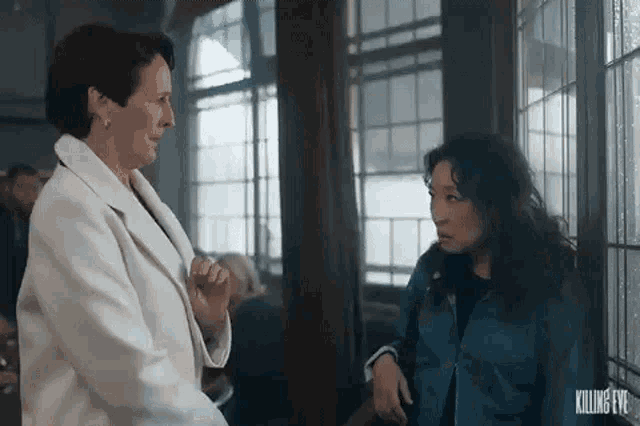 two women are standing next to each other in a room .