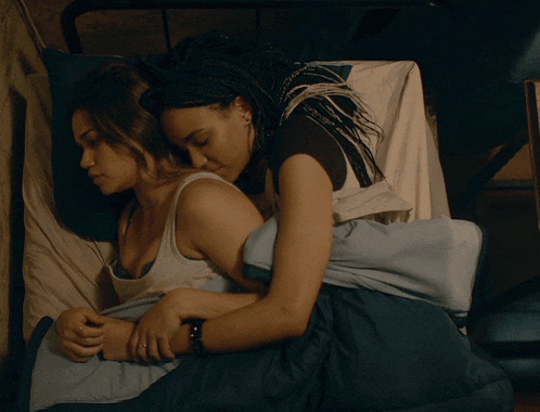 two women are hugging each other while laying on a bed