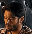 a man with a beard is sitting in a chair with his eyes closed and looking down .