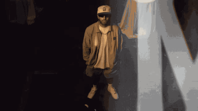a man wearing a hat with the letter n on it stands in a dark room