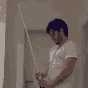a man with a beard is holding a light saber in a hallway .