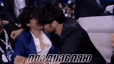a man kissing another man in a crowd with a congratulations message in russian
