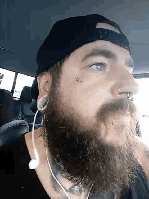 a man with a beard wearing a hat and earbuds