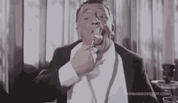 a man in a tuxedo is holding a spoon in his mouth .