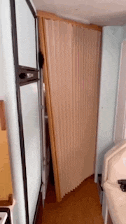 a room with a sliding door that is open and a couch in the corner .