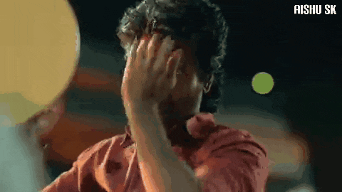 a man in a red shirt is covering his face with his hand