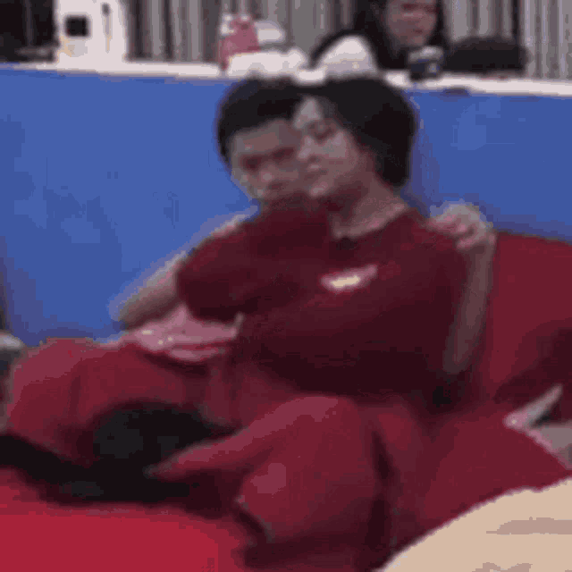 a couple of people are sitting on a red couch and hugging each other .