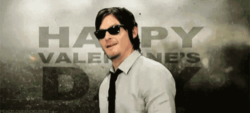 a man wearing sunglasses is smiling in front of a happy valentine 's day poster