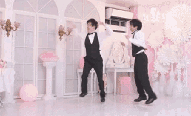 a couple of men are dancing in a room with pink walls