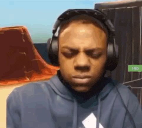 a man wearing headphones and a blue hoodie is looking down .