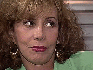 a close up of a woman 's face with a green shirt and earrings .